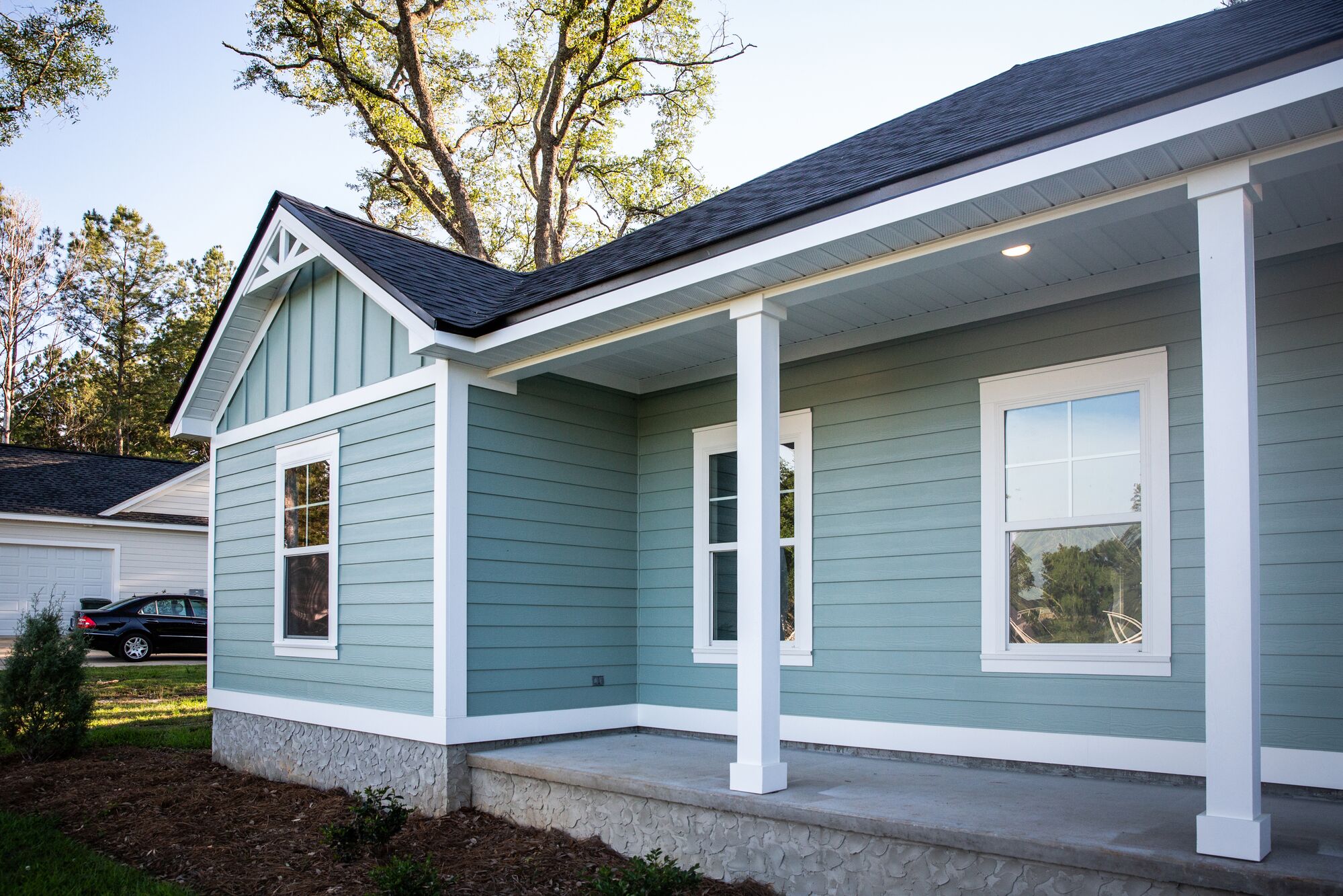 Light blue home exterior featuring decorative gables, white trim, and a covered porch. Lush landscaping adds appeal for potential buyers.