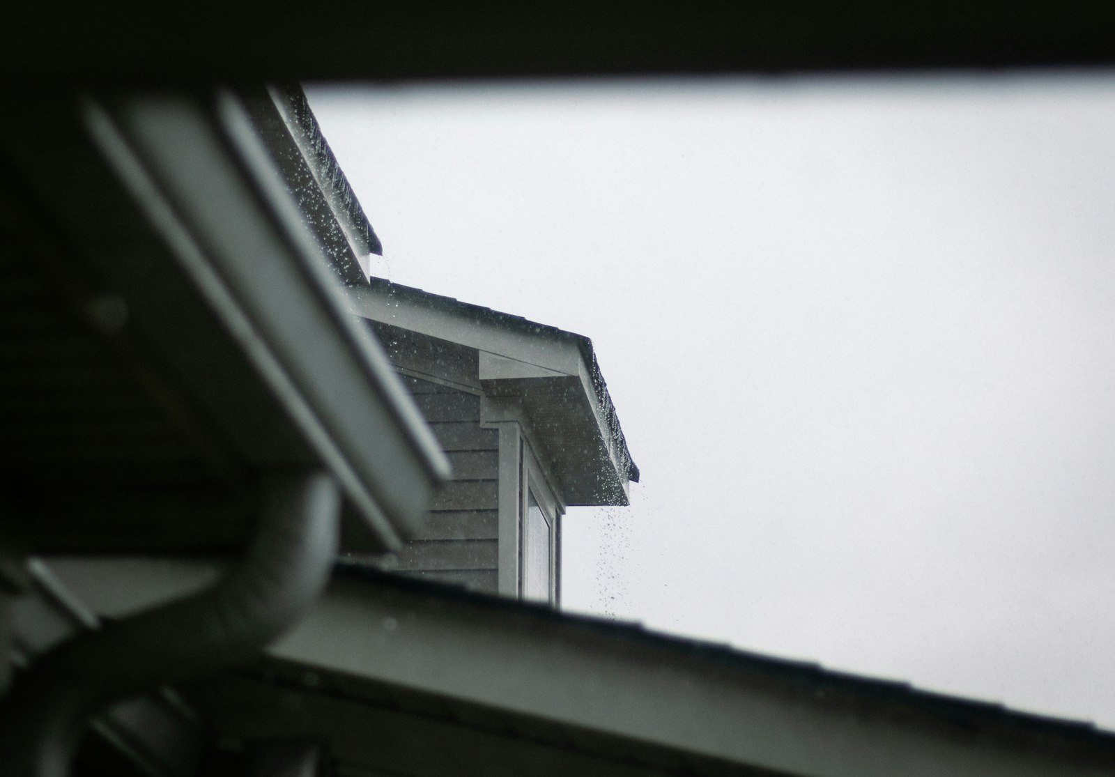 A house roofline and gutter system against a grey sky